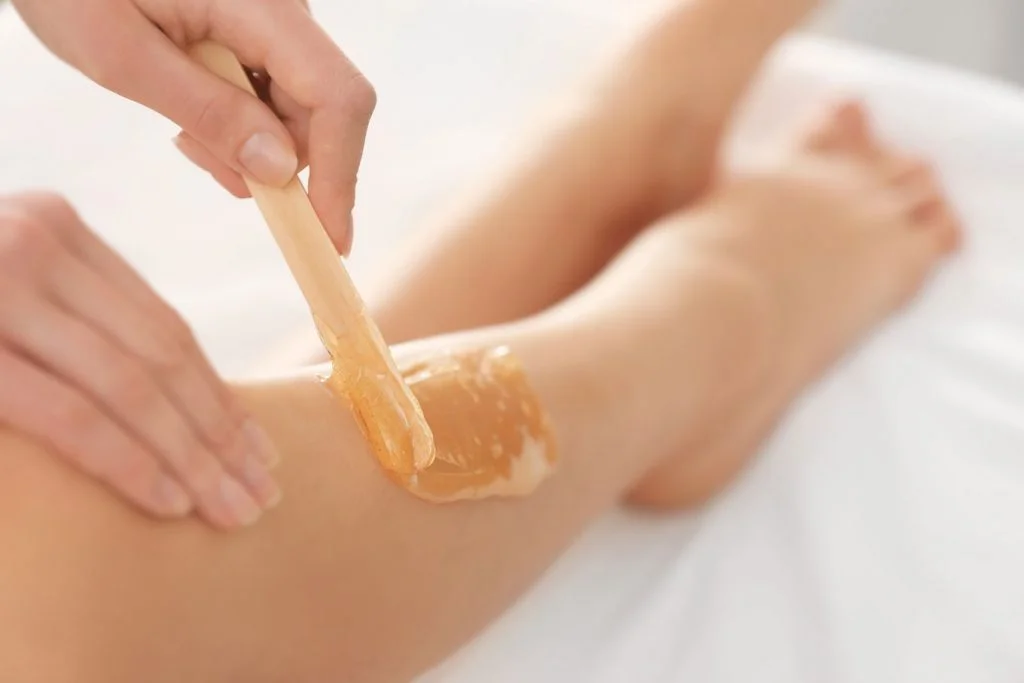 Jambe d'une femme avec de la cire appliquée pour l'épilation.